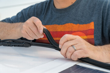 Man installing a split wire loom conduit for a solar panel wire connections