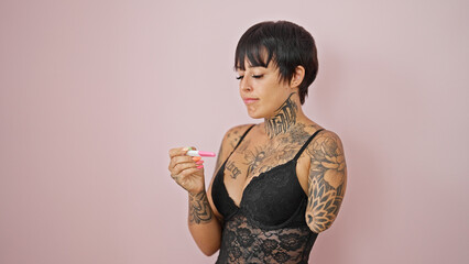Hispanic woman with amputee arm wearing lingerie looking pregnancy test over isolated pink...