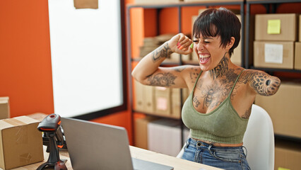 Hispanic woman with amputee arm ecommerce business worker using laptop celebrating at office