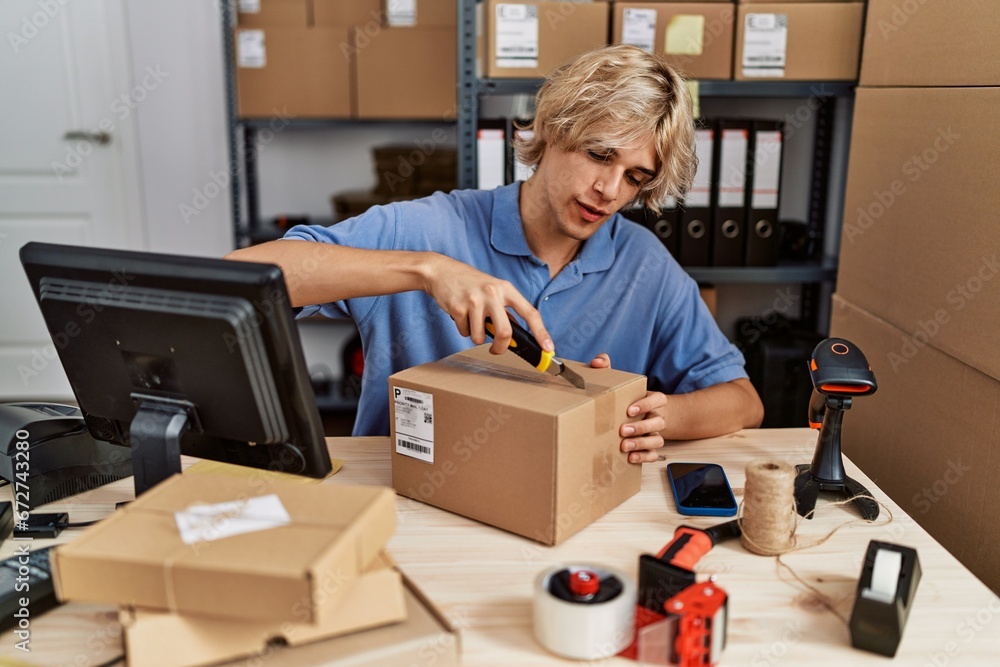 Poster Young blond man ecommerce business worker unpacking cardboard box at office