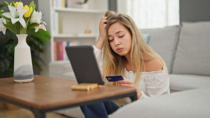 Young blonde woman having video call shopping with credit card at home