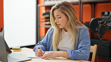 Young blonde woman musician writing song at music studio