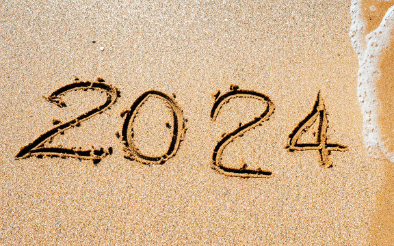 Símbolo do novo ano de 2024. Novo ano de 2024 desenhado na areia da praia. A onda lavará a inscrição 2024