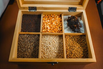 Brown wooden box with multiple sections containing a variety of grains. Indian spices for kitchen.