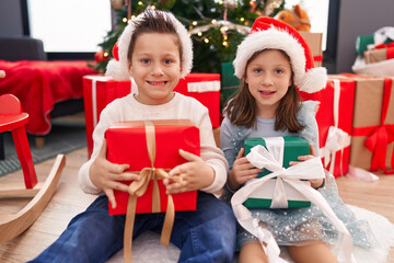 Fototapeta na wymiar Adorable boy and girl smiling confident holding christmas gift at home