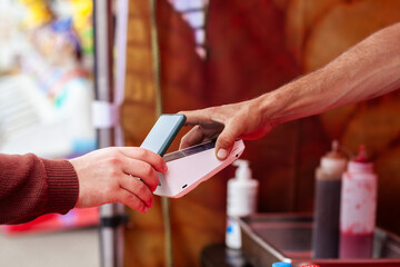 Man using phone to tap and pay for food at market stall