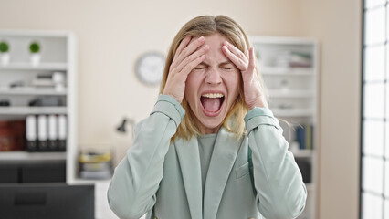 Young blonde woman business worker stressed screaming at office