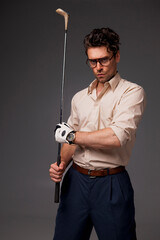 Confident and stylish man in eyeglasses holding golf club isolated on grey 