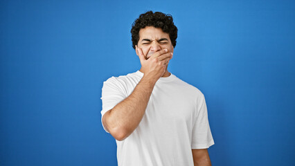 Young latin man tired yawning over isolated blue background