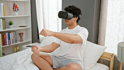 Young latin man playing video game using virtual reality glasses driving car at bedroom