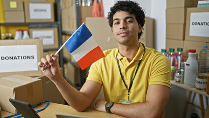 Young latin man volunteer holding french flag at charity center