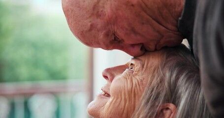 Kiss forehead, love and senior couple by window for bonding, marriage and relationship at home. Retirement, relax and elderly man and woman embrace for commitment, care and trust in living room