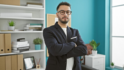 Young arab man business worker standing with arms crossed gesture and serious face at the office