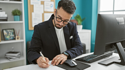 Young arab man business worker using computer taking notes at the office