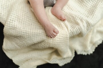 Closeup of the feet of a newborn baby on a cozy white bedspread