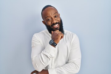 African american man standing over blue background with hand on chin thinking about question, pensive expression. smiling and thoughtful face. doubt concept.