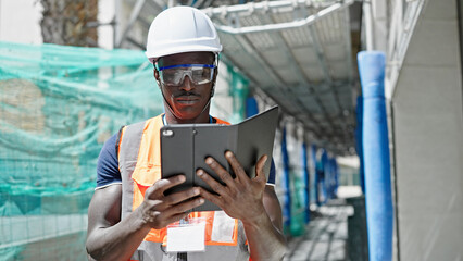 African american man builder using touchpad at construction place