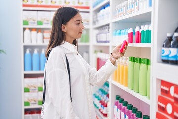 Young beautiful hispanic woman client holding toothpaste at pharmacy