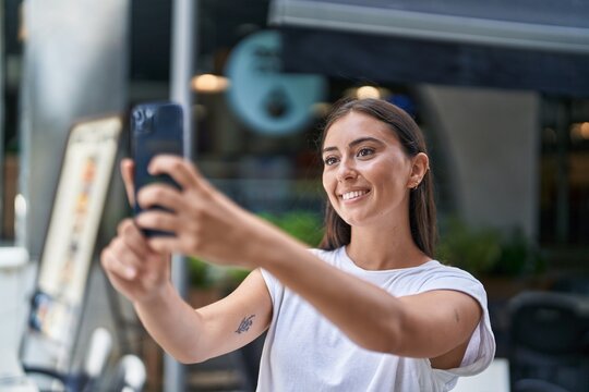 Young beautiful hispanic woman smiling confident making selfie by the smartphone at coffee shop terrace