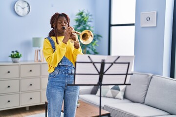 African american woman musician playing trumpet at home
