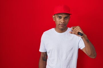 Young hispanic man singing song using microphone thinking attitude and sober expression looking self confident