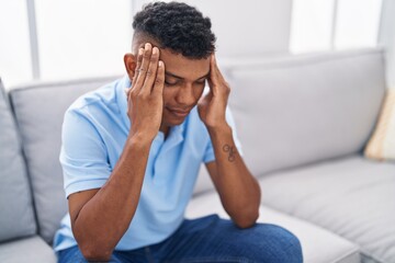 Young latin man stressed sitting on sofa at home