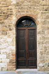 Fototapeta na wymiar Elegant old double door entrance of building in Europe. Vintage wooden doorway of ancient stone house. Simple brown wood door. Architecture in Italy.