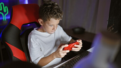 Adorable blond boy streamer, engrossed in serious game playing, live streaming his smartphone game...
