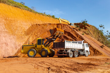 Backhoe dumps earth into truck bucket during construction in the city of Guarani, state of Minas Gerais, Brazil.