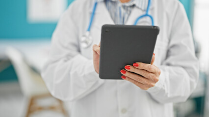 Middle age woman doctor using touchpad at clinic