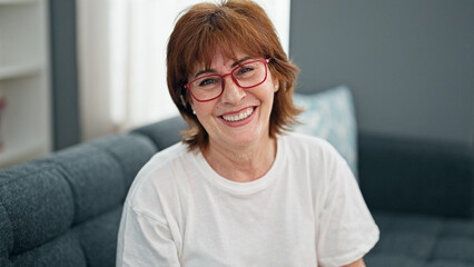 Fototapeta premium Middle age woman wearing glasses sitting on sofa home