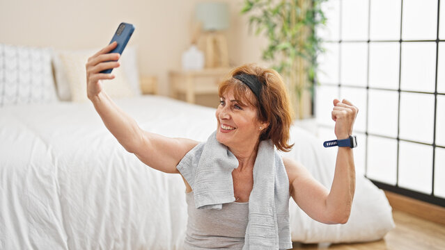 Middle age woman sitting on floor doing strong gesture with arm at bedroom