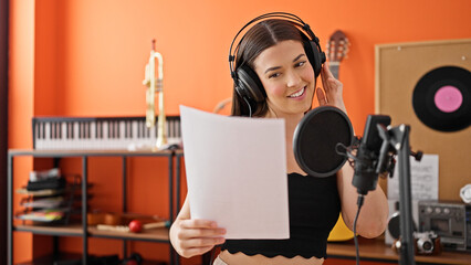 Young beautiful hispanic woman musician smiling confident singing song at music studio