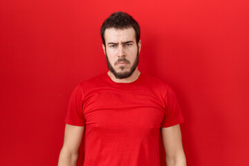 Young hispanic man wearing casual red t shirt depressed and worry for distress, crying angry and...