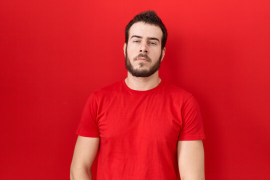 Young hispanic man wearing casual red t shirt relaxed with serious expression on face. simple and natural looking at the camera.