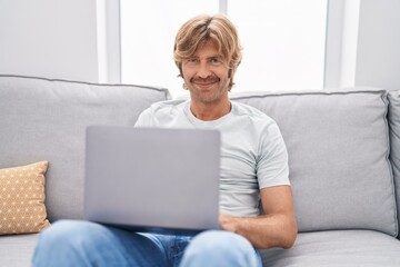 Young man using laptop sitting on sofa at home