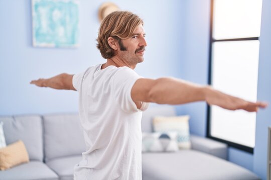 Young blond man training yoga at home