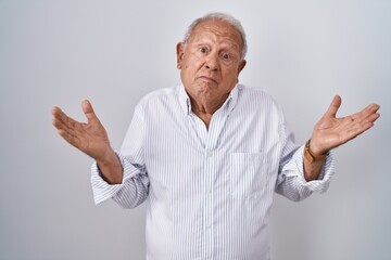 Senior man with grey hair standing over isolated background clueless and confused expression with...