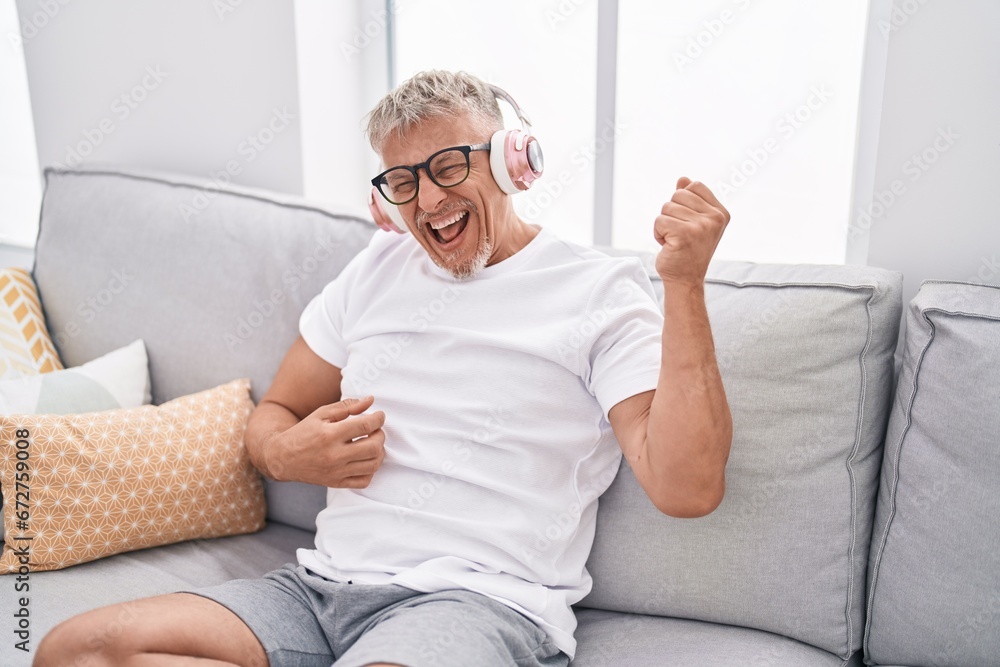 Sticker middle age grey-haired man listening to music doing guitar gesture at home