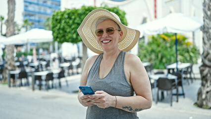 Middle age grey-haired woman tourist smiling confident using smartphone at coffee shop terrace