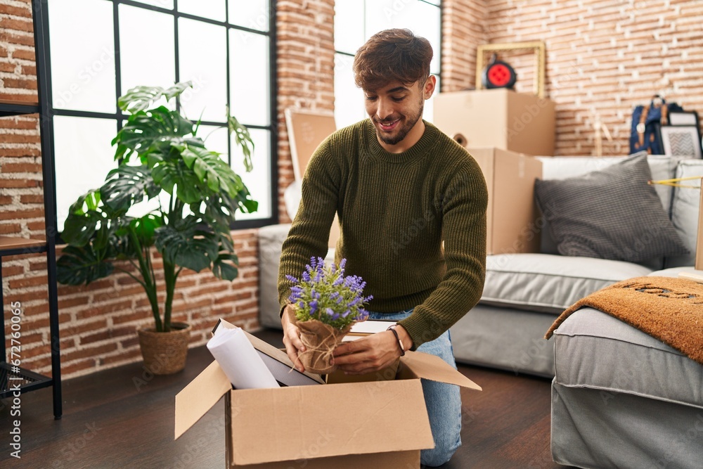 Poster Young arab man smiling confident unboxing lavander plant at new home