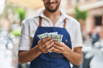 Young arab man waiter counting dollars working at restaurant