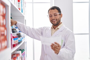 Young man pharmacist organize shelving reading shelving at pharmacy
