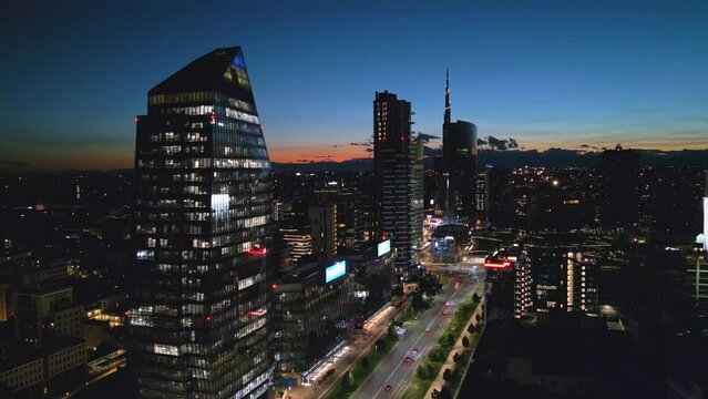 aerial view drone of milan city skyline illuminated at night dusk,flying over business financial area with modern building skyscrapers