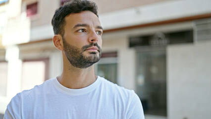 Fototapeta premium Young hispanic man looking to the side with serious expression at street