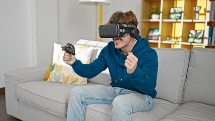 Obraz premium Young hispanic man playing video game using joystick and virtual reality glasses at home