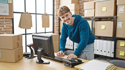 Young hispanic man ecommerce business worker using computer standing at office