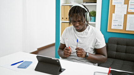 Naklejka na ściany i meble African american man business worker listening to music doing drummer gesture at the office