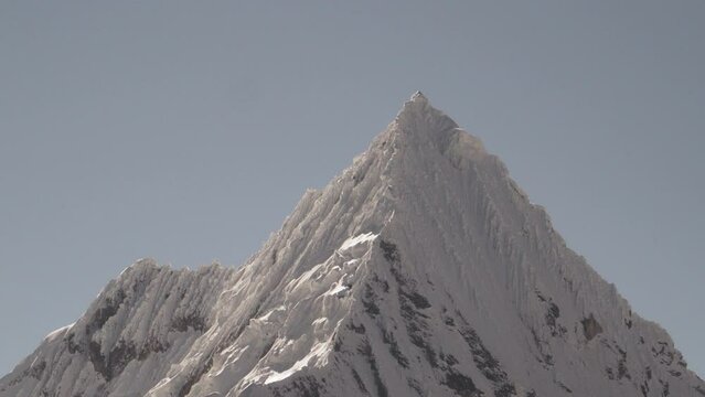 ice covered glacier of a pyramid shaped mountain at laguna paron lagoon in the high andes mountains of the cordillera blanca at huascaran, Peru, with snow covered mountain peaks on a bright sunny day.