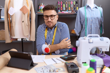 Hispanic man with beard dressmaker designer working at atelier shaking and freezing for winter cold with sad and shock expression on face